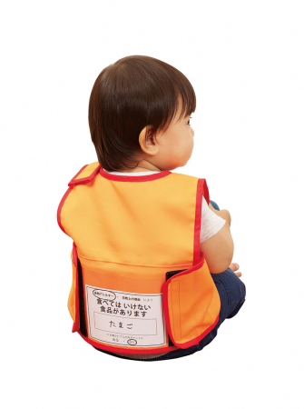 ▲使用例　　目立ちやすいオレンジカラーの防炎加工生地。　園児の情報カードを入れるポケット付。